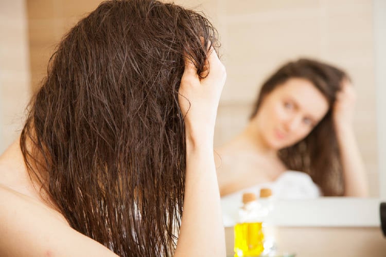 Una mujer aplica aceite en su cabello